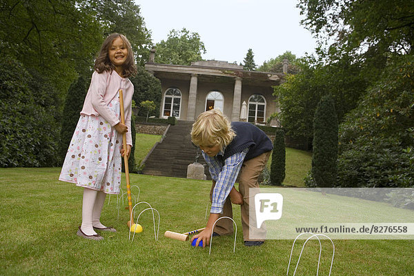 Zwei Kinder spielen Krocket im Park