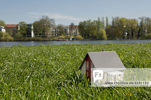 Ein Miniaturhaus auf der Wiese am Ufer eines Flusses