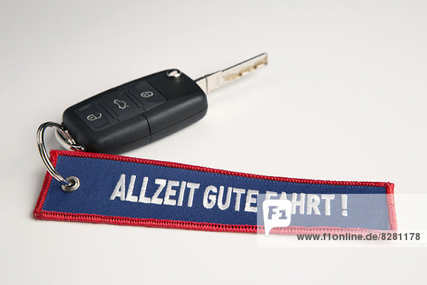Ein Autoschlüssel und Schlüsselanhänger mit dem Satz Always Drive Good in German Allzeit Gute Fahrt!
