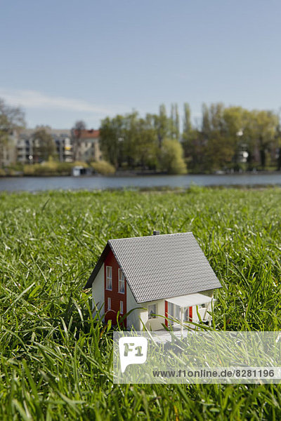 Ein Miniaturhaus auf der Wiese am Ufer eines Flusses