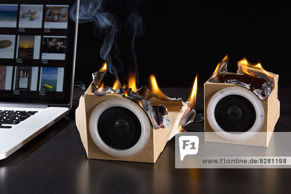 Zwei umweltfreundliche Audio-Lautsprecher aus Pappe brennen neben einem Laptop