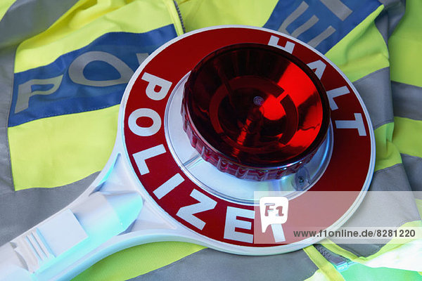 Eine deutsche Polizei-Reflexjacke und ein deutsches Handstoppschild mit Halt Polizei