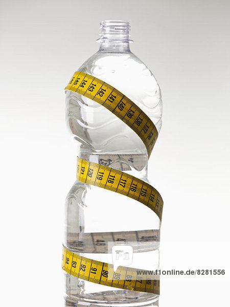 A plastic water bottle full of water and wrapped with a tape measure