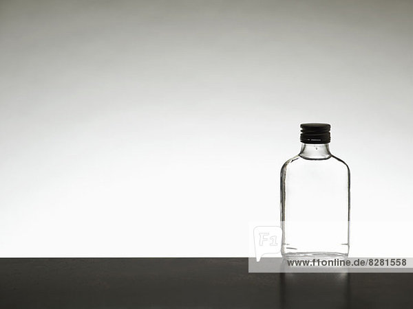 A miniature bottle of alcohol without a label  back lit