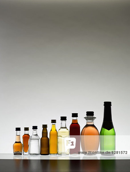 Eine Linie von verschiedenen Miniaturflaschen Alkohol ohne Etiketten  hinterleuchtet