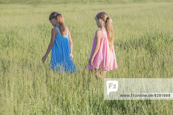 Ein junges Mädchen folgt seiner Schwester und geht durch ein sonniges Feld.