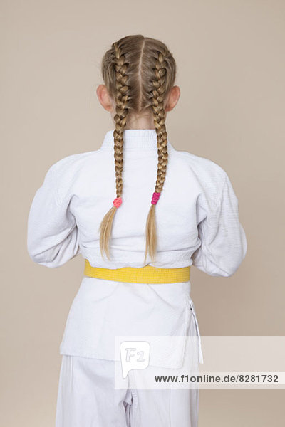 Ein Mädchen in Kampfsportuniform mit gelbem Gürtel  Rückansicht