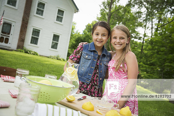 Eine Sommer-Familienzusammenkunft auf einem Bauernhof. Zwei Kinder stehen Seite an Seite. Herstellung von hausgemachter Limonade.