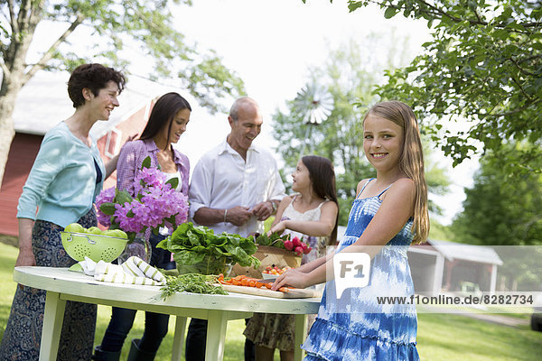 Familienfeier. Ein gedeckter Tisch mit Salaten und frischem Obst und Gemüse. Eltern und Kinder. Zwei Mädchen,  eine junge Frau und ein reifes Paar.