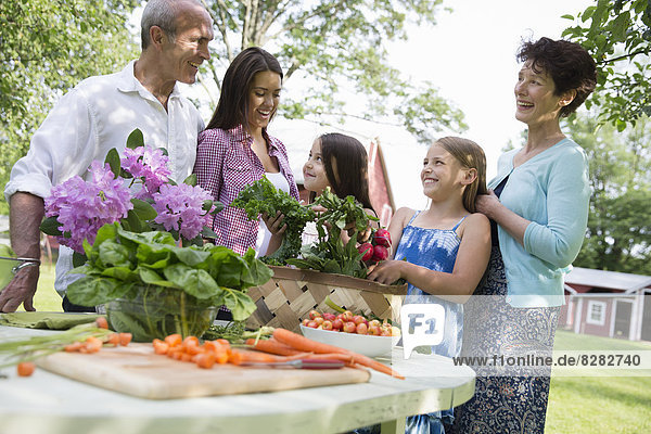 Familienfeier. Ein gedeckter Tisch mit Salaten und frischem Obst und Gemüse. Eltern und Kinder.