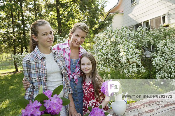 Three People Gathering Flowers And Arranging Them Together. A Mature Woman  A Teenager And A Child.