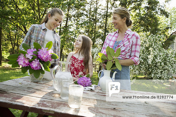Drei Menschen sammeln Blumen und arrangieren sie gemeinsam. Eine reife Frau  ein Teenager und ein Kind.