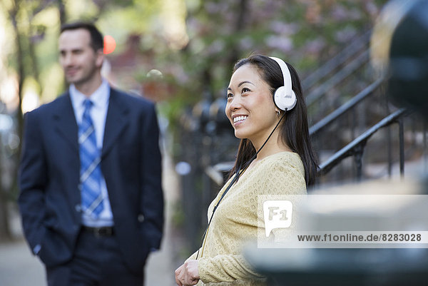 A Woman Wearing Music Headphones  And A Man In A Business Suit.