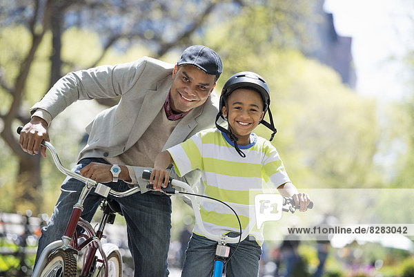 A Family In The Park On A Sunny Day. Father And Son Bicycling