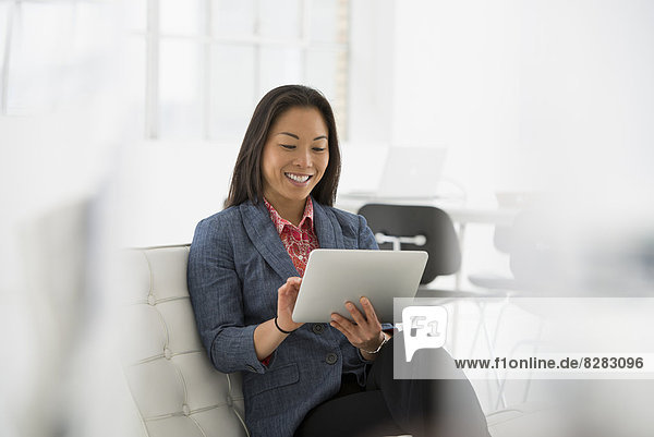 Business. A Woman Sitting Down Using A Digital Tablet.