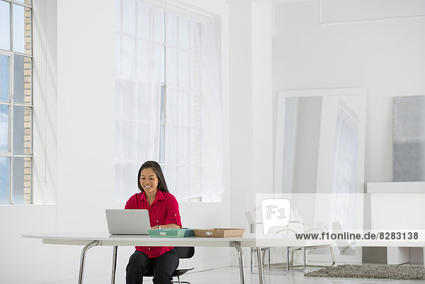 Leichte und luftige Arbeitsumgebung. Eine Frau sitzt mit einem Laptop.