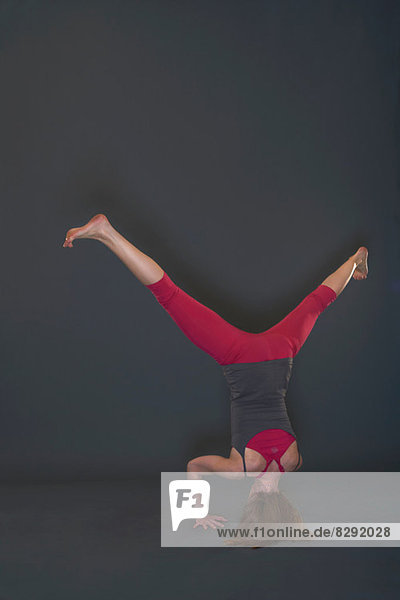 Frau in Yoga-Pose auf grauem Hintergrund