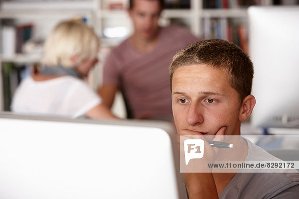 Young man using computer  hand on chin