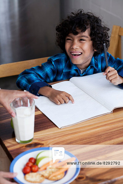 Junge macht Hausaufgaben  Person  die Snacks und Milch serviert