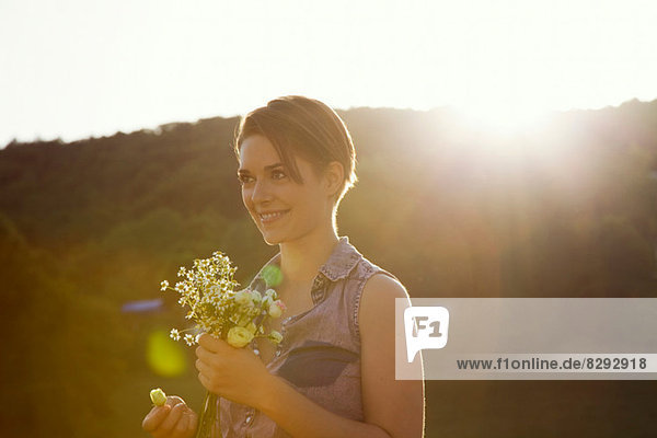 Junge Frau auf der Wiese mit Wildblumenstrauß