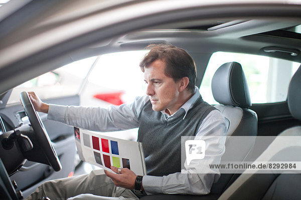 Mid adult man checking dashboard in car showroom