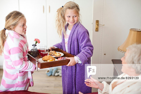 Enkelinnen geben Großmutter Frühstück im Bett