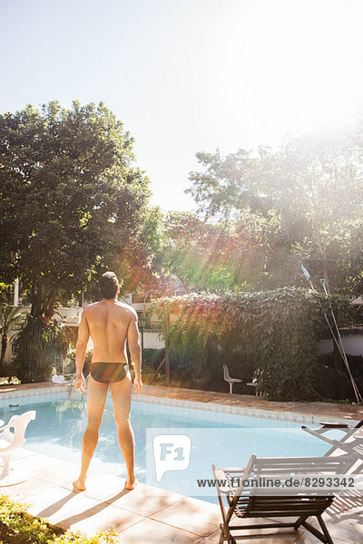 Mann im Sonnenlicht am Pool stehend