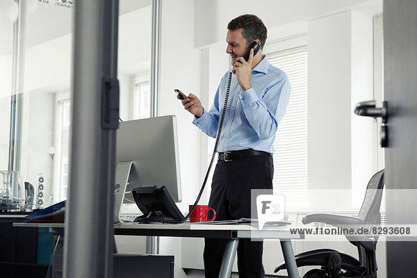 Mature businessman on landline phone in office