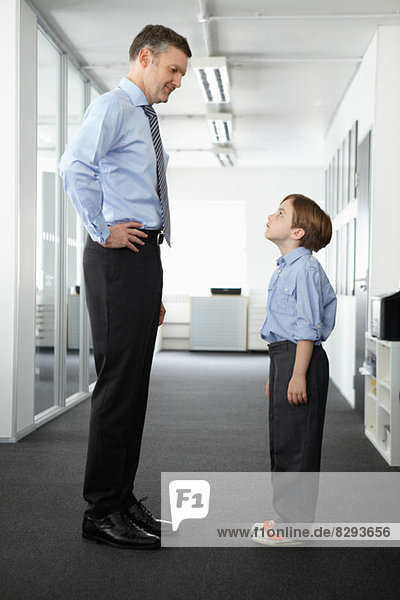 Father and son standing face to face in office