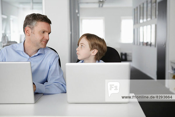 Vater und Sohn mit Laptops  von Angesicht zu Angesicht