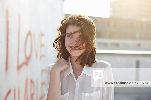 Portrait of young woman by wall with graffiti