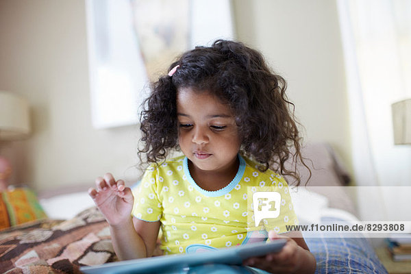 Kind auf dem Bett sitzend mit digitalem Tablett