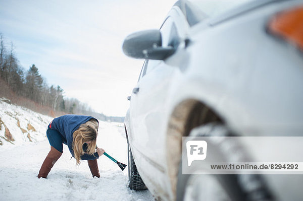 Frau grabt Auto aus dem Schnee heraus