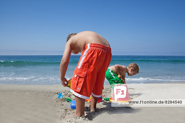 Zwei junge Brüder bauen Sandburgen am Strand