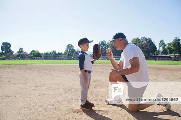 Mann im Gespräch mit Enkel auf dem Baseballfeld