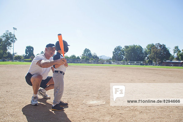 Man teaching grandson to play baseball