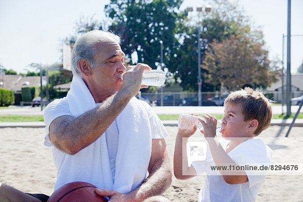 Mann und Enkel trinken gemeinsam Wasser in Flaschen