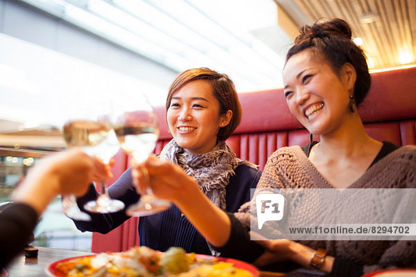 Junge Frauen toasten mit Wein im Restaurant