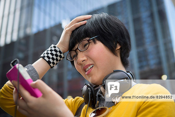 Young woman using mp3 player with hands in hair