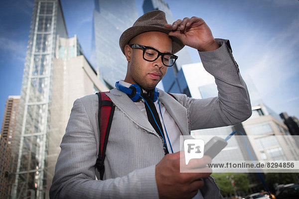 Young man wearing hat and glasses using mp3 player