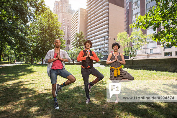 Three young people doing yoga in park