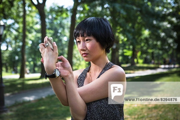 Young woman holding smartphone with arms twisted