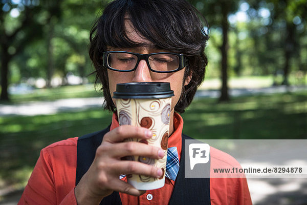 Junger Mann inhaliert Kaffee aus Einwegbecher