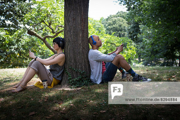 Young couple leaning against tree trunk