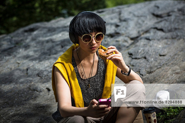 Young woman eating snack with mp3 player