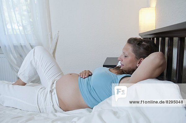young pregnant woman lying on bed