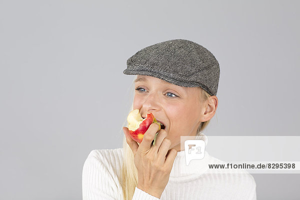 Junge Frau mit Hut  die einen Apfel isst