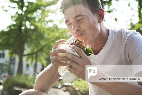 Junger Mann isst Hamburger