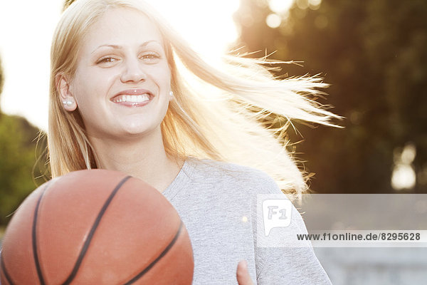 Lächelnde junge Frau mit Basketball