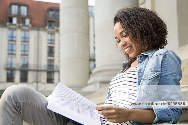 Young woman sitting on steps  reading book